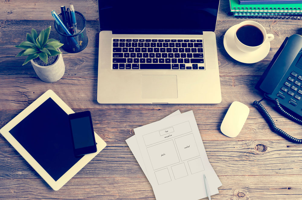 laptop, phone, and ipad on rustic desk