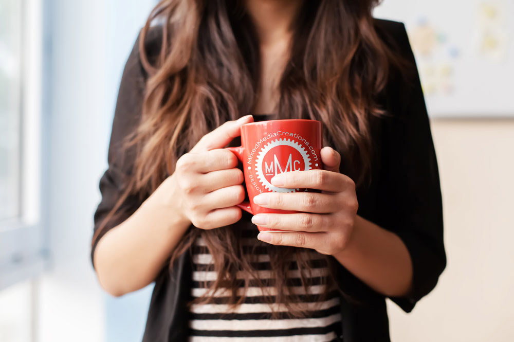 woman holding cup of coffee with MMC on it