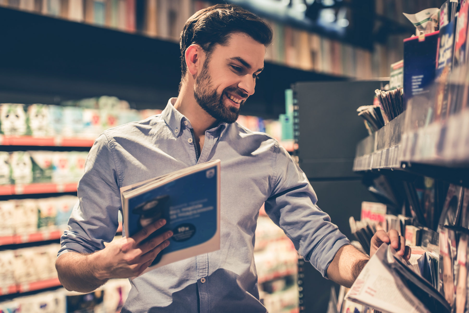 man in bookstore looking at magazines
