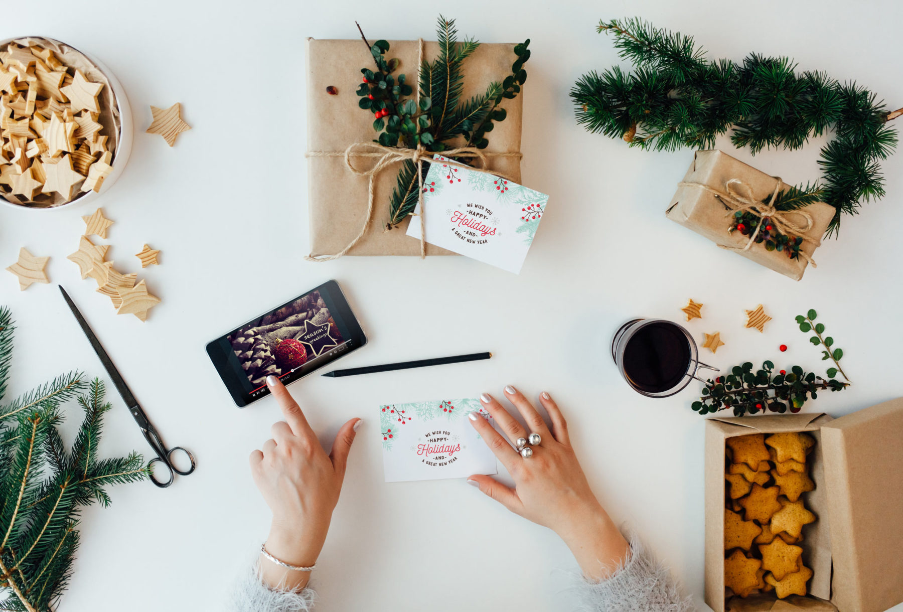 woman pointing at iphone on table with christmas decorations